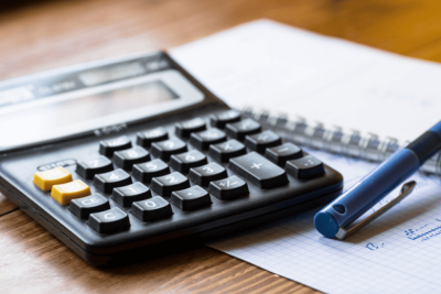 Calculadora e caneta sobre folha quadriculada – simbolizando o processo de calcular hora extra.