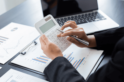 Pessoa usando calculadora financeira ao lado de planilhas e gráficos para simular a TAE.