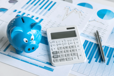 Cofrinho azul e calculadora sobre gráficos financeiros, representando cálculo de salário líquido e bruto.