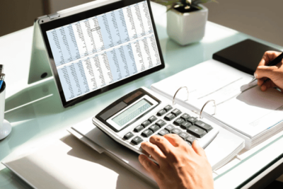 Pessoa calculando FGTS com planilha e calculadora no escritório.